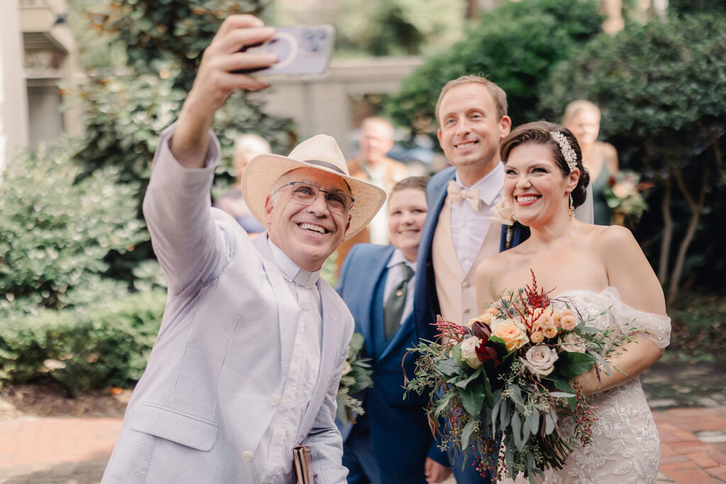 Officiant snaps photo with bride and groom